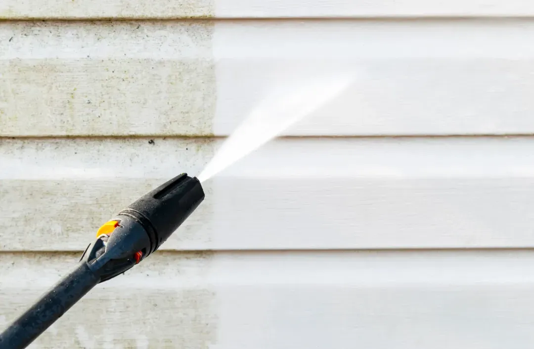 Pressure washer spraying water on brick patio, cleaning between pavers